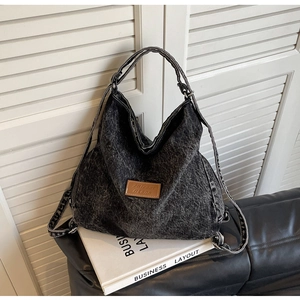 Dettaglio della borsa tote in denim grigio con patch logo in pelle su sfondo minimal