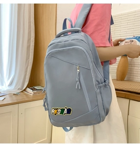 Light blue nylon backpack with RKDBAG patch shown in a lifestyle setting on a model
