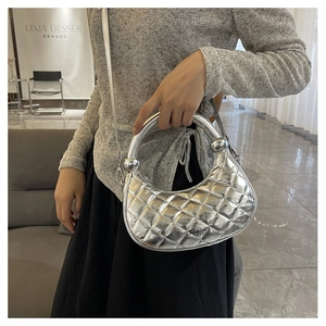 Close-up of silver quilted crossbody bag with metal sphere detail and detachable strap