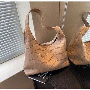 Close-up of khaki shoulder bag featuring unique 3D wave texture and soft leather finish