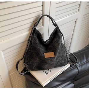 Dettaglio della borsa a tracolla in denim nero lavato con etichetta in pelle marrone sul sacco