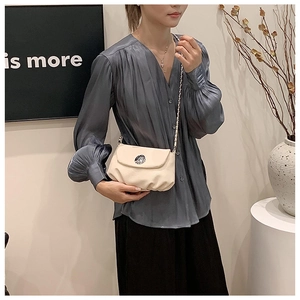 Asiatisches Model mit cremeweißer Satteltasche, silberner Metallschnalle und Kettenriemen