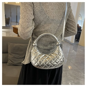 Silver quilted crescent bag shown on a model with metallic finish and round handle