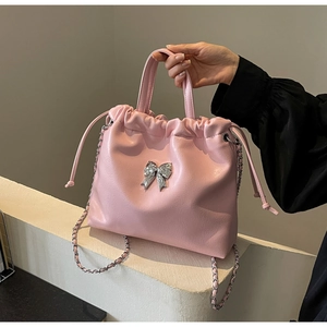 Vue détaillée du sac bourse rose avec ornement nœud argenté et bandoulière chaîne