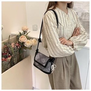 Detail of grey patterned bucket bag with black knotted strap and pearl bow charm