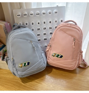 Close-up of light blue and pink nylon backpacks with front zip pockets on wooden surface