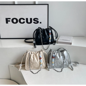 Détail de sacs seaux matelassés en noir, beige et argent avec bandoulières perlées
