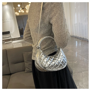 Silver quilted hobo bag with round metal ball handle shown on model side-view