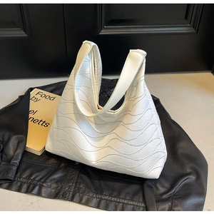 Detail of white tote bag featuring unique wavy pleated texture and wide shoulder strap
