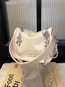 Sac polochon beige en cuir avec chaîne argentée et breloque cheval tenu à la main