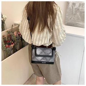 Detailed view of quilted crossbody bucket bag with pearl charm and rope knot strap
