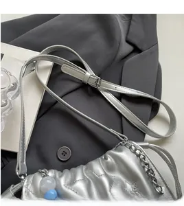 Détail du sac seau argenté matelassé avec coutures en étoile et perles bleues