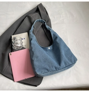 Détail du sac hobo en denim bleu avec fermoir à pression argenté et design incurvé élégant