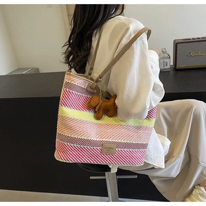 Dettaglio borsa tote bohémien intrecciata a righe colorate con ciondolo in pelle