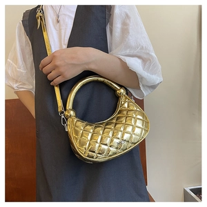 Detail of a gold metallic quilted hobo bag with round handle and detachable shoulder strap