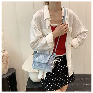Detail of light blue quilted crossbody bag with a pearl butterfly charm and YOLO BAG logo