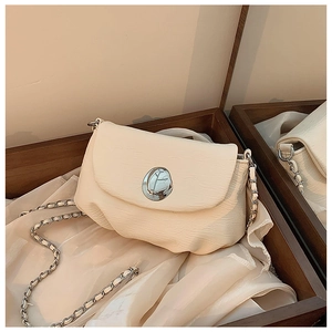 Detail der cremefarbenen Satteltasche mit silberner Metallschnalle und Kettenriemen