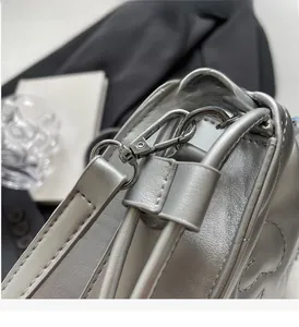 Détail macro du sac en cuir nacré argenté avec boucle métallique et coutures précises