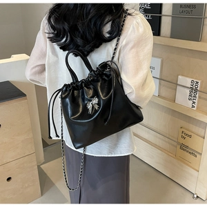 Vue détaillée d'un sac seau noir avec nœud argenté porté par un mannequin féminin