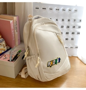 Detail view of cream nylon backpack featuring multi-pocket design and RKOBAG embroidered logo