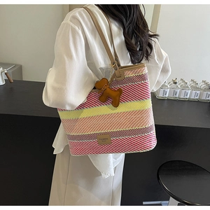 Dettaglio della borsa tote boho intrecciata a righe colorate con ciondolo cane