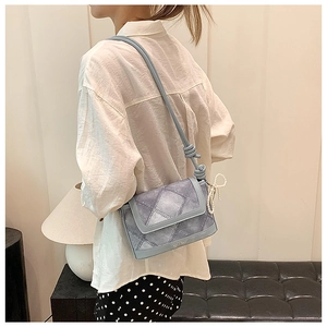 Detail of light blue bucket bag with denim texture, knot strap and pearl bow charm
