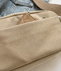 Detailaufnahme der praktischen Vordertasche einer beigen Canvas-Crossbody-Brusttasche