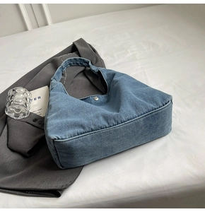 Détail du sac hobo en denim bleu avec fermoir magnétique argenté et texture sergé