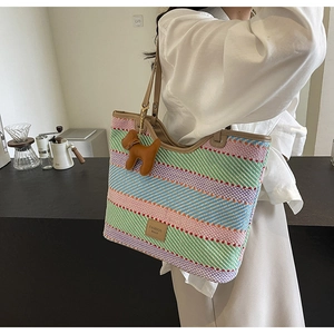 Dettaglio della borsa tote in paglia a righe colorate con ciondolo in pelle