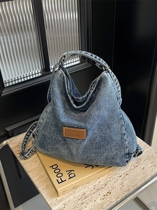 Grande borsa hobo in denim con toppa in pelle su tavolino in marmo moderno
