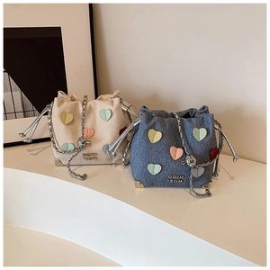 Close-up of heart-shaped patches and silver chain on pleated bucket handbags