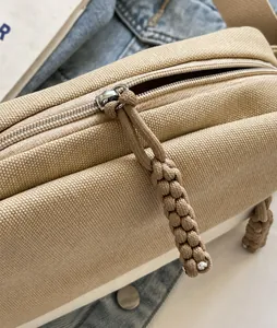 Detail eines silbernen Reißverschlusses mit Kordelzug an einer Khaki-Segeltuchtasche