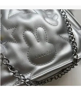 Détail de la chaîne argentée sur sac matelassé avec motifs de lapins et d'étoiles