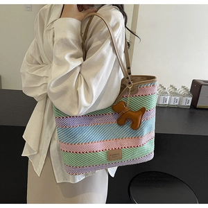 Dettaglio della borsa tote intrecciata colorata con manici in pelle marrone e charm