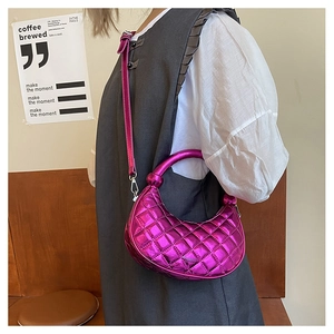 Detail of metallic pink crescent bag with diamond quilting and round handle on model