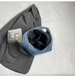 Détail du sac en jean avec poche intérieure zippée et texture plissée sur le côté du sac
