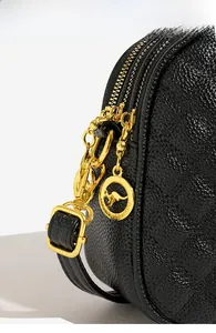 Gros plan du sac en cuir noir avec double fermeture éclair dorée et breloque