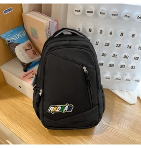 Close-up of black nylon backpack with RKDBAG embroidery on light wooden desk