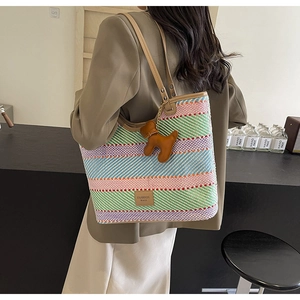 Dettaglio della borsa tote in paglia colorata con tracolla in pelle e ciondolo a cane