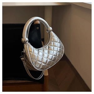Detail of silver quilted dumpling bag with metallic finish and round handle on chair