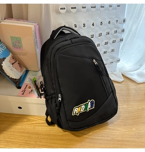 Detail of black nylon backpack with RKDBAG embroidery on desk with study props