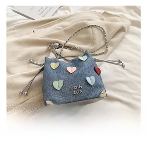 Detail of blue denim bucket bag featuring colorful heart appliqués and metal chain strap