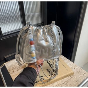 Détail du sac seau matelassé argenté avec motifs étoiles et breloque en perles