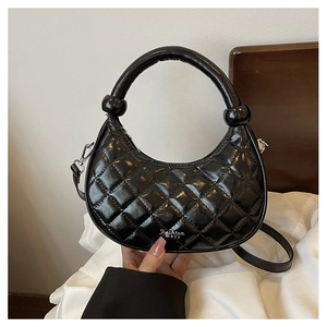 Macro detail of black quilted dumpling bag with glossy finish and silver metal hardware