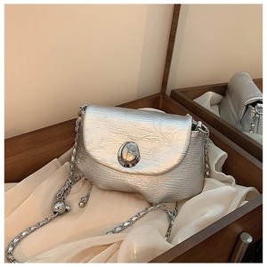 Detail der silbernen Satteltasche mit plissierter Metallic-Textur und polierter Metallschnalle