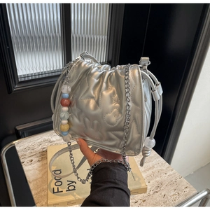 Détail du sac seau matelassé argenté avec motifs d'étoiles et breloque perlée