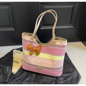 Dettaglio della borsa tote intrecciata a righe colorate con manici in pelle e ciondolo