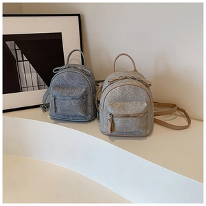 Detail shot of mini backpacks in light blue and beige with crinkled PU leather texture
