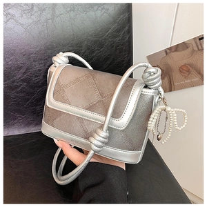 Detail of grey textured fabric handbag with silver metal trim and pearl bow charm