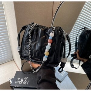 Détail du sac seau noir plissé avec des perles colorées et une bandoulière en chaîne